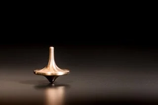 A spinning top toy on a dark surface